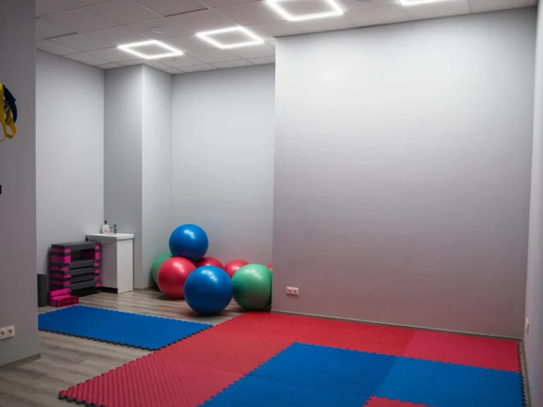 Sala rehabilitacji CRMed w Gliwicach — czerwono-niebieskie maty, piłki gimnastyczne i taśmy TRX